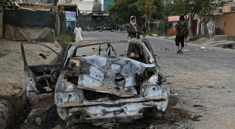 Los talibanes al lado de un coche destrozado tras el impacto de misiles contra Kabul, Afganistán, el 30 de agosto de 2021. Foto: AFP