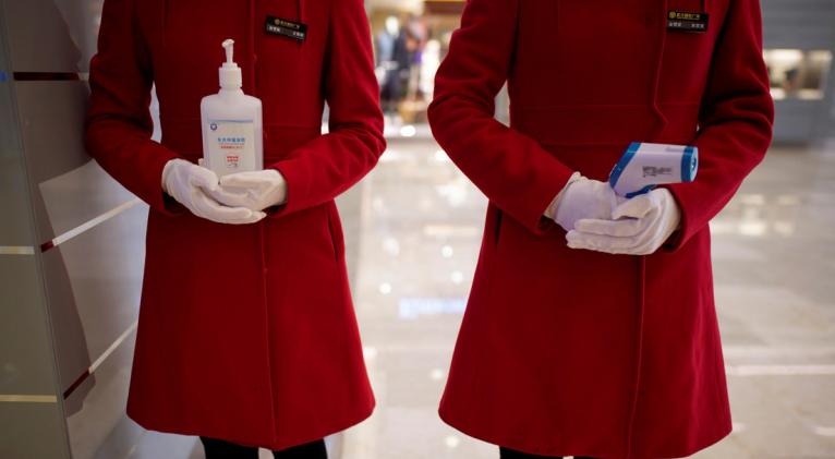 Empleados con un desinfectante y un termómetro en la entrada de un centro commercial, Wuhan, China, el 30 de marzo de 2020. Foto: Reuters