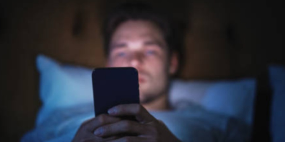 Joven en cama revisando celular Joven en cama revisando celular