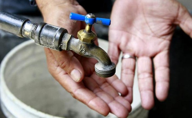 Manos esperando bajo una llave de agua