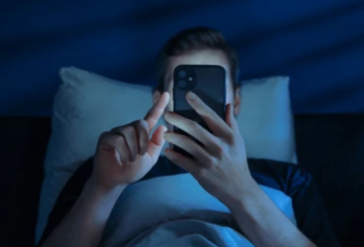 Joven mirando el cell en la cama