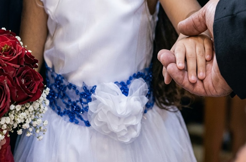 Detalle de manos de novia menor de edad y anos de novio en la boda